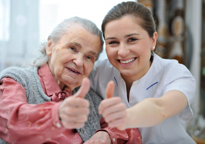 caregiver and elderly woman signing thumbs up